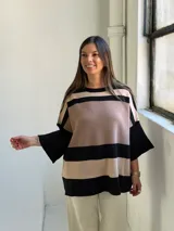 Poncho de tejido de punto con diseño de rayas horizontales anchas en color negro y beige, de corte holgado y mangas anchas.
