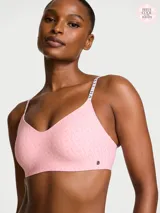 Bralette inalámbrico de escote pronunciado, color rosado con estampado de logotipos en tono más oscuro y tirantes ajustables con la marca impresa. Cuenta con relleno ligero transpirable y tejido de microfibra suave.