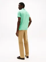 Chomba verde agua de Tommy Hilfiger, corte regular, con cuello tipo chomba, cartera de dos botones, logo bordado en el pecho y mangas cortas.