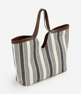 Cartera shopper de algodón con diseño a rayas en tonos neutros y detalles de ribetes y asas de hombro en PU marrón. Cuenta con una abertura central pronunciada y gran capacidad de almacenamiento.