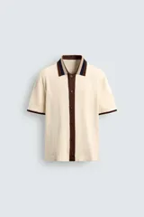 Camisa de punto de algodón con corte relajado, cuello solapa y manga corta. Presenta un diseño bicolor en tonos beige y marrón, con cierre frontal de botones.