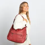 Cartera tipo hobo de cuero sintético color rojo ladrillo, con correa de hombro ajustable. Tiene cierre superior con solapa y broche magnético, bolsillo frontal con cierre, bolsillos laterales con cierre y múltiples bolsillos internos.