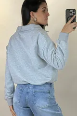 Buzo deportivo color blanco con cuello polo y cierre frontal parcial. Presenta mangas largas con puños elásticos y ruedo ajustable con cordón elástico.