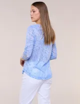 Blusa celeste con estampado floral devoré, de manga tres cuartos, escote redondo amplio y detalle de pechera de encaje blanco en contraste.