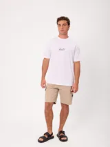 Remera blanca Rusty de corte holgado, con cuello redondo y mangas cortas. Presenta un estampado en la espalda de estilo veraniego con palmeras, una tabla de surf y letras alusivas a la marca.