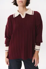 Sweater de punto color marrón con cuello polo en contraste color crema. Presenta diseño de rayas verticales texturizadas, mangas largas con puños en color crema y corte holgado.