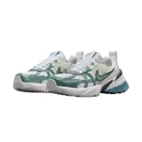 Championes Nike V2K Run de estilo retro-futurista, con diseño en capas de malla y material sintético en tonos beige y gris. Presenta una entresuela robusta con tecnología Cushlon y el logo de Nike en el lateral.