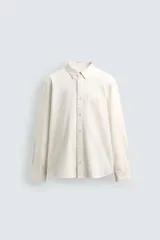 Camisa de corte relajado confeccionada en tejido de algodón, con cuello solapa, manga larga con puños abotonados, bolsillo frontal en el pecho y cierre de botonadura.