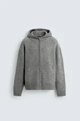 Chaqueta de punto con capucha, corte relajado, manga larga, bolsillos laterales y cierre frontal con cremallera. Presenta acabados en rib en puños y bajo.