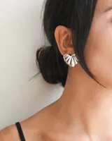 Par de aros plateados con forma de corazón con textura acanalada.