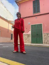 Pantalón rojo de corte recto y tiro alto, con bordado tipo broderie en la parte inferior de las piernas.
