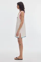 Vestido corto de tejido calado estilo red, color blanco, con escote redondo, sin mangas y ribetes en contraste de colores en cuello, sisas y dobladillo.