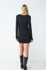 Vestido mini negro de manga larga con diseño ceñido, detalles cut-out en el pecho y los hombros, y lazos ajustables.