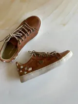 Championes de cuero color terra con diseño pintado a mano en el talón, cordones claros y suela de goma blanca.