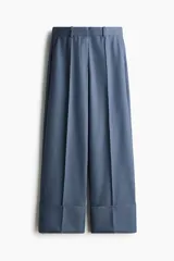 Pantalón sastrero de sarga color azul, de corte recto y pierna ancha, con pliegues frontales y doblez ancho en los bajos.