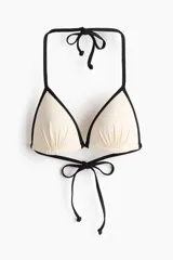Top de bikini de triángulo con copas acolchadas preformadas y diseño fruncido, en color blanco con ribetes negros y tiras ajustables para atar al cuello y la espalda.