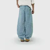 Pantalón de jean con corte ultra baggy, de tiro medio y diseño con costuras decorativas curvas en las piernas. Presenta una silueta amplia y holgada con acabado en denim clásico.