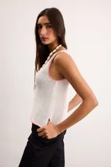 Musculosa de punto color blanco crudo, con escote en V y terminaciones con bordado artesanal amarillo.