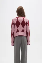 Cardigan de punto con diseño de rombos en tonos rosa y bordó. Presenta cierre frontal mediante lazos anudados, cuello redondo y mangas largas con puños acanalados.