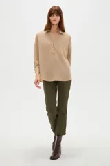 Blusa holgada de poliéster color beige, con cuello camisero, escote en V con botones frontales y mangas largas.