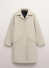 Chaqueta larga de algodón color beige, de diseño recto, manga larga, cuello camisero y cierre delantero con botones ocultos. Cuenta con dos bolsillos laterales con solapa.