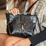 Bandolera negra de cuero vacuno con textura tipo cocodrilo, correa larga ajustable y removible, cierre superior y bolsillo con cierre en la tapa trasera. Interior forrado con bolsillo para celular.