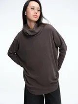 Sweater de tejido de punto en color gris oscuro, con silueta amplia y cuello polera holgado. Presenta mangas largas con ajuste en los puños y un diseño de calce cómodo y moderno.