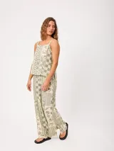 Pantalón largo de corte ancho, color verde y beige, con estampado geométrico y motivos marinos.