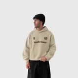 Hoodie de algodón color beige con capucha, bolsillo frontal tipo canguro y estampado gráfico en el pecho con el logo de la marca Venefo Chosen.