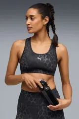 Top deportivo Puma modelo 4 Keeps de color negro, con diseño animal print sutil en tonos oscuros, espalda nadadora de malla y el logo de la marca estampado en blanco en el centro del frente.