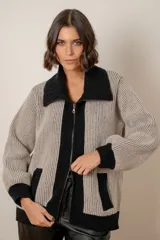 Campera de punto confeccionada en lana, con diseño bicolor en tonos beige y negro. Presenta cuello solapa, cierre frontal con doble cursor, bolsillos laterales y puños tejidos en contraste.