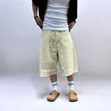 Bermuda de corte baggy color beige crema, con costura vertical trasera en cada pierna y detalle artesanal visible en el bajo. Incluye un cordón extra confeccionado en la misma tela.