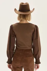 Pantalón wide leg de cuero sintético color marrón, con tajo frontal en el ruedo y cierre de botón y cremallera.