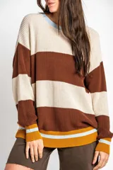 Sweater oversize de tejido de punto con diseño de rayas horizontales en tonos beige, marrón, mostaza y celeste. Presenta cuello redondo, mangas largas y puños y ruedo acanalados.