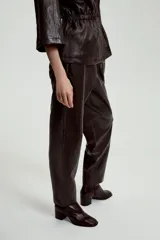Pantalón de tiro alto confeccionado en material efecto piel, con cintura elástica ajustable mediante cordones, bolsillos delanteros y bolsillos de plastrón en la parte trasera.