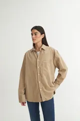 Camisa marrón de pana fina con cuello solapa clásico, bolsillo cuadrado en el pecho, botones personalizados y calce oversize.