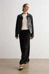 Pantalón de corte recto y tiro medio, confeccionado en tejido negro de textura sutil. Presenta un diseño minimalista con cierre frontal oculto y caída fluida.