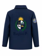 Campera impermeable de tela taslon color azul marino, con diseño de escudo bordado en la espalda y parche circular con la bandera de Uruguay en la manga. Presenta cierre frontal y puños ajustables.