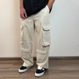 Pantalón tipo jean cargo de corte baggy, color beige, con cuatro bolsillos laterales de gran tamaño con solapa.