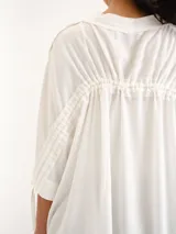 Remerón blanco de corte holgado, mangas cortas amplias y cuello bote con jareta.