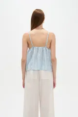 Musculosa blanca de algodón con diseño de broderie, escote en V, tirantes finos regulables y corte holgado.