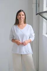 Remera de algodón color blanco, con cuello en V, mangas largas y corte holgado con costuras visibles en el ruedo.