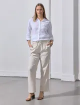 Pantalón de lino de corte recto y tiro medio, con pretina elástica ancha y lazo de ajuste frontal. Presenta bolsillos laterales verticales y bolsillos traseros.