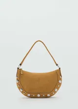 Bolso de hombro tipo hobo en color tostado, confeccionado en piel bovina con acabado de gamuza. Presenta un diseño semicircular decorado con tachuelas metálicas plateadas en el contorno inferior y cierre de cremallera superior.