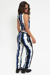 Pantalón de corte recto y tiro medio-alto, confeccionado en crepé con estampado geométrico en tonos azul, blanco y negro. Cuenta con pretina, cierre y botón frontal.