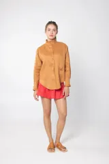 Camisa de manga larga color camel, confeccionada en lino, con cuello mao y detalle de volado en los puños.