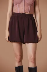 Short de tiro alto en color bordó, con diseño tipo globo y cintura elástica que incluye un cinturón al tono con hebilla forrada.