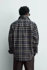 Camisa relaxed fit de franela de algodón, con diseño a cuadros en tonos azul marino, verde y blanco. Cuenta con cuello camisero, manga larga con puños abotonados, bolsillos de parche en el pecho y cierre frontal con botones.