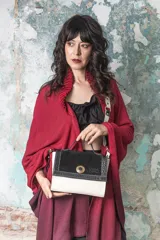 Cartera bandolera estructurada de cuero, con panel superior de gamuza negra y panel inferior de cuero blanco. Asa corta rígida forrada en cuero y correa larga desmontable con detalles metálicos dorados.