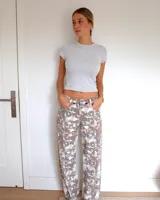 Pantalon de corte recto con estampado camuflado en tonos neutros, beige y marron. Presenta costuras verticales frontales que recorren el largo de las piernas, bolsillos laterales y cierre frontal con boton.